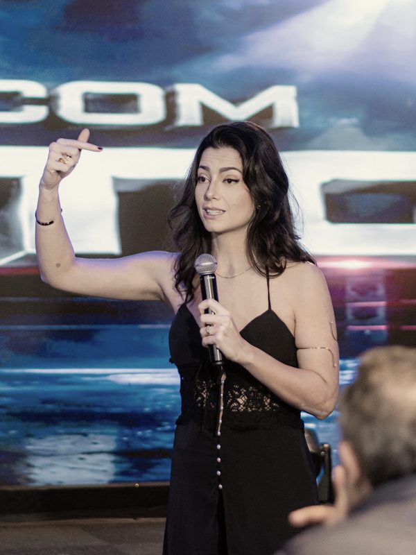 Kath Zaparoli falando ao microfone no palco